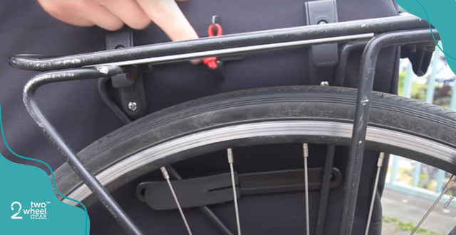 A hand on a mounting rack attaching a pannier.