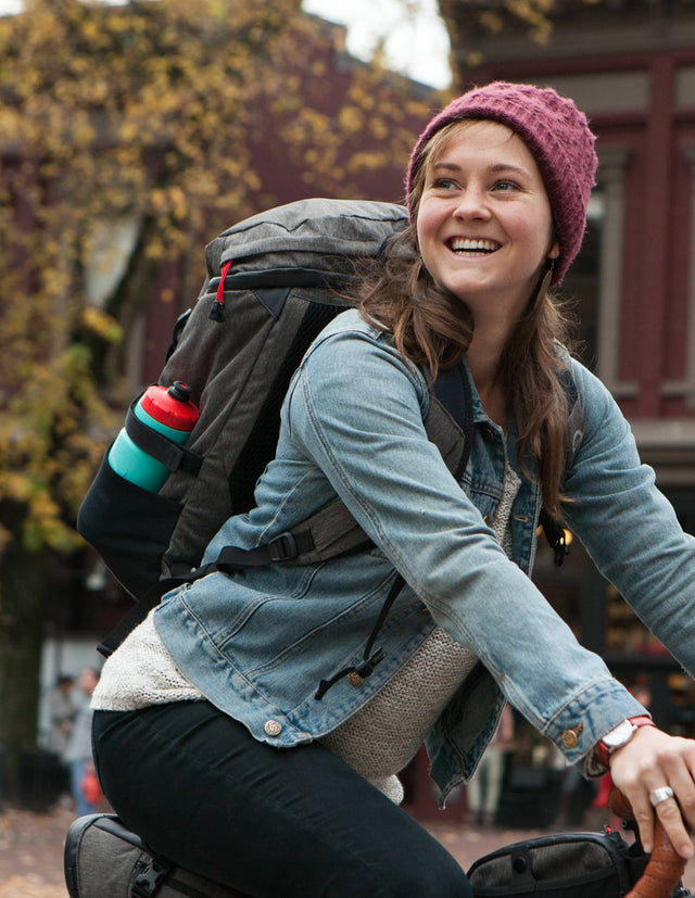 Happy woman riding her bike with wearing a Two Wheel Gear Commute Backpack.