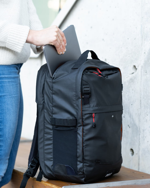 Woman putting a laptop into the Two Wheel Gear Pannier Backpack 2.0 Plus