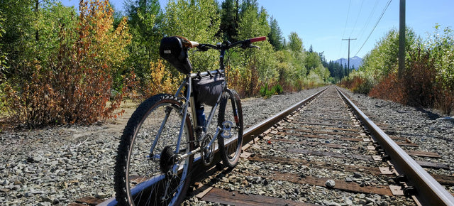 Bike resting on train tracks on a beautiful sunny day.