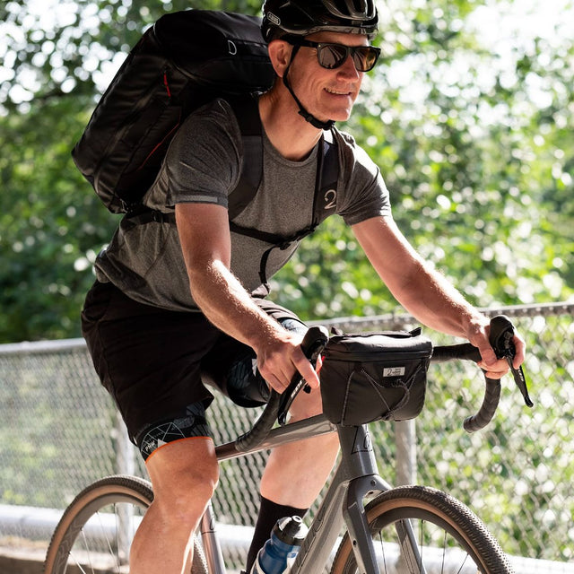 Man riding bicycle with Two Wheel Gear handlebar bag and backpack