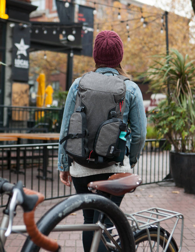 Woman walking away from her bike wearing a Two Wheel Gear Commute Backpack 3 Bag Kit.