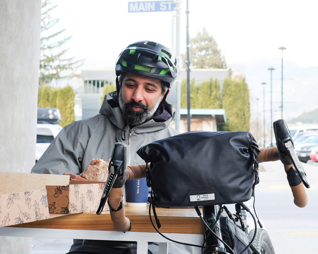 Man having coffee and a donut next to his bike with Dayliner Handlebar bag.